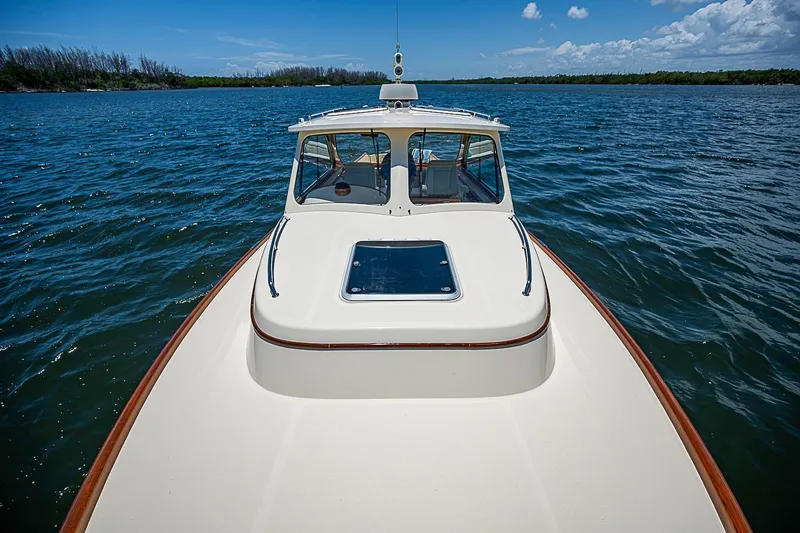 Slide: The Image of 2013 Hinckley Talaria 34 yacht cruising on a serene lake under a clear blue sky. - 18