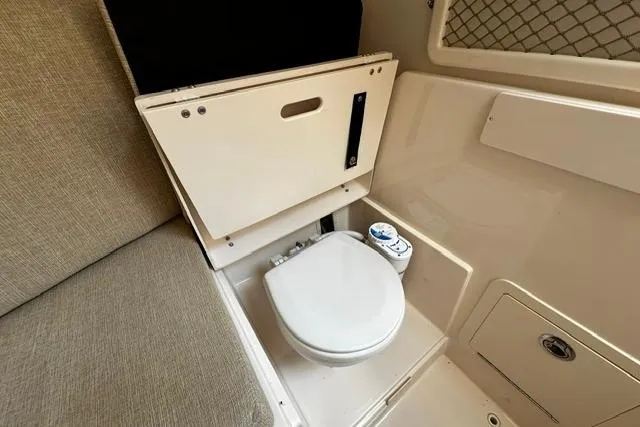 Slide: The Image of 2025 Grady-White Gulfstream 232 boat interior with compact marine toilet and seating area. - 39