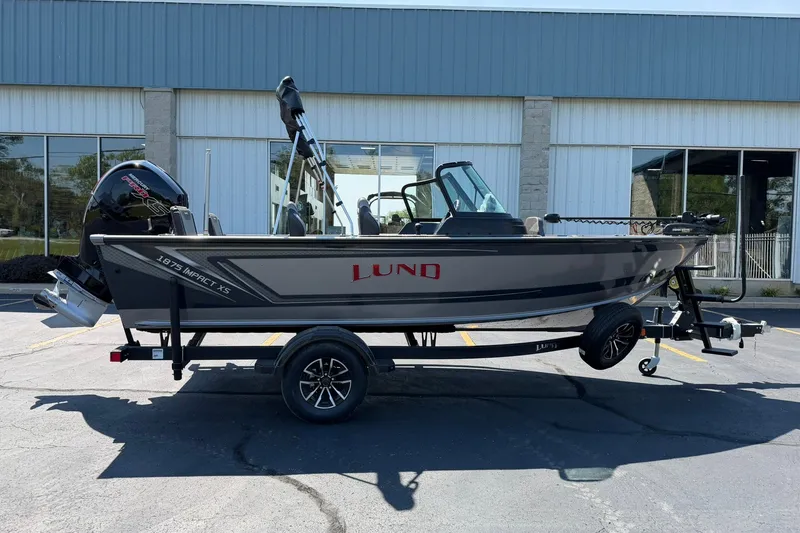 Slide: The Image of 2027 Lund 1875 Impact XS Sport boat on trailer, parked outside a building. - 24