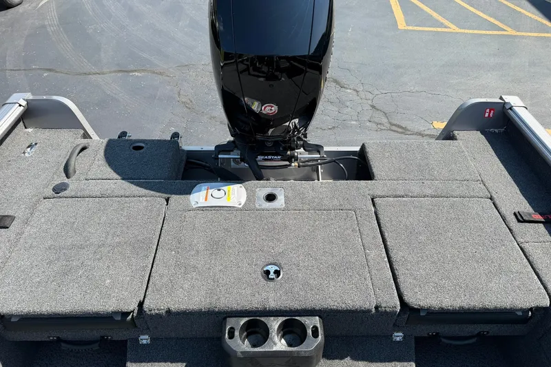Slide: The Image of 2027 Lund 1875 Impact XS Sport boat deck with motor, featuring gray carpet and storage compartments. - 11