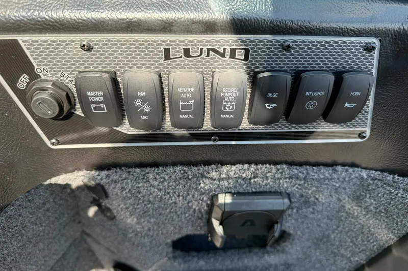 Slide: The Image of Control panel of 2027 Lund 1875 Impact XS Sport boat with various switches. - 17