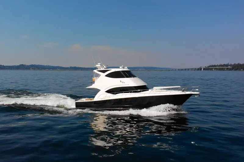 The Image of 2012 Riviera 33 Flybridge yacht cruising on open water under clear skies. - 0