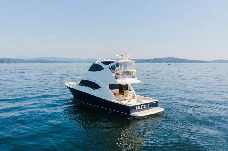 Slide: The Image of 2012 Riviera 33 Flybridge yacht cruising on a serene lake under a clear sky. - 38