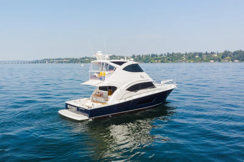 Slide: The Image of 2012 Riviera 33 Flybridge yacht cruising on a serene lake with distant shoreline. - 37