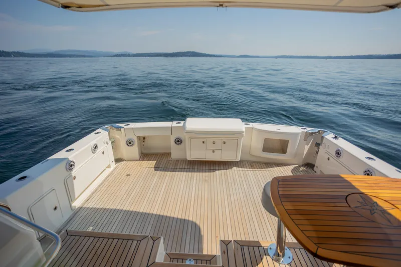 Slide: The Image of 2012 Riviera 33 Flybridge yacht deck with ocean view and wooden table. - 27