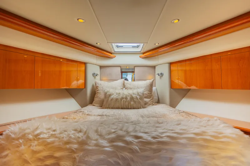 Slide: The Image of Luxurious interior of 2012 Riviera 33 Flybridge yacht with plush bedding and wooden cabinetry. - 9