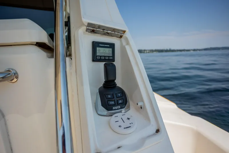 Slide: The Image of Control panel of 2012 Riviera 33 Flybridge yacht with joystick and display, overlooking calm waters. - 30