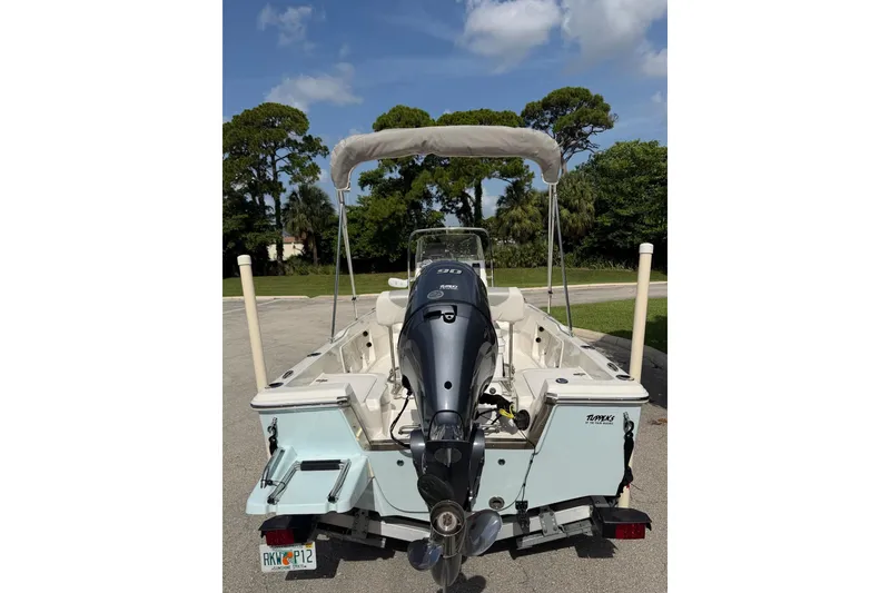Slide: The Image of 2024 Key West 1720 Center Console boat with outboard motor and canopy, parked outdoors. - 7