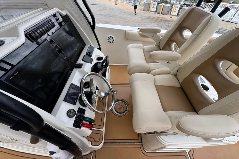 Slide: The Image of 2015 Sailfish 320 CC boat cockpit with dual beige captain chairs and modern control panel. - 14