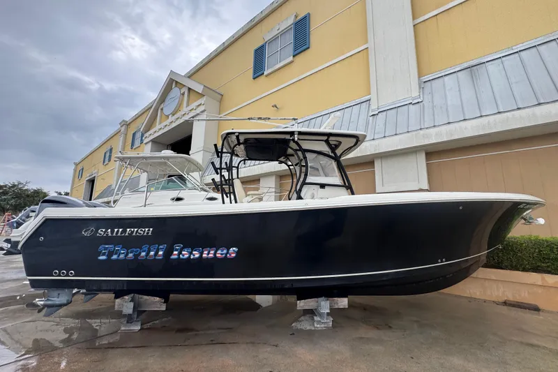 Slide: The Image of 2015 Sailfish 320 CC boat named "Thrill Issues" on display outside a building. - 2