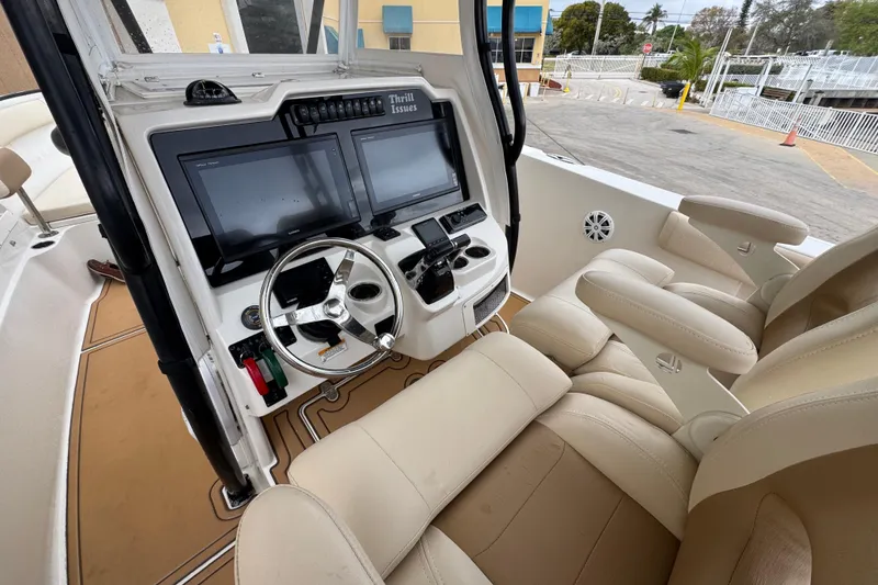 Slide: The Image of 2015 Sailfish 320 CC boat cockpit with dual screens and beige seating. - 15
