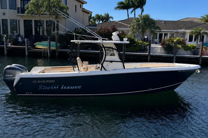 Slide: The Image of 2015 Sailfish 320 CC boat docked near waterfront homes, featuring Yamaha engines. - 0