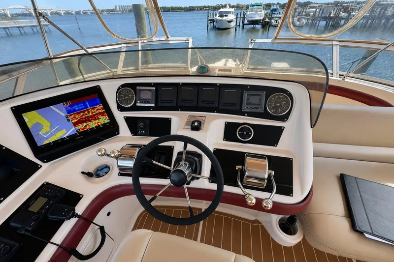 Slide: The Image of 2003 Sea Ray 45 Express Bridge helm with navigation screens and controls, overlooking marina. - 4