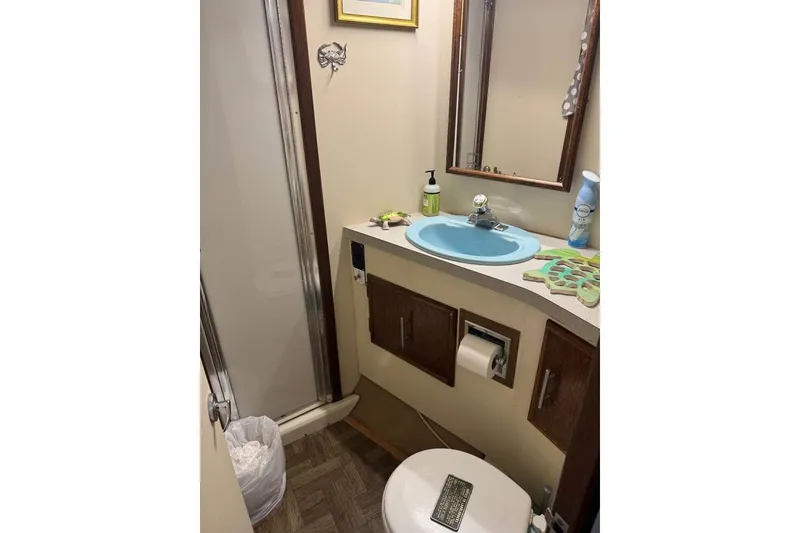 Slide: The Image of 1979 Post 42 Convertible bathroom with blue sink, shower, and wooden cabinets. - 8