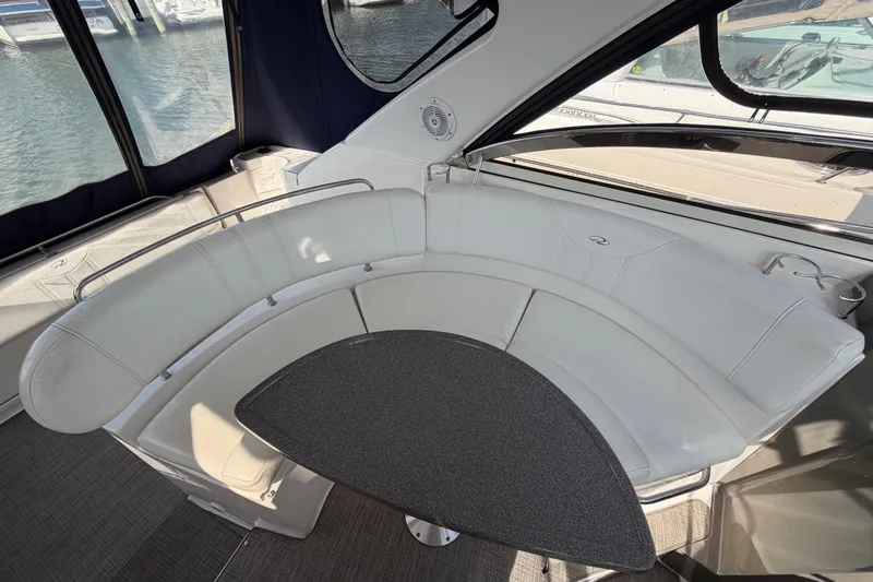Slide: The Image of 2007 Regal Commodore 3760 IO boat interior with curved seating and table, docked at marina. - 10