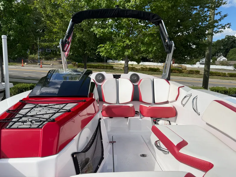 Slide: The Image of The image shows a 2017 Scarab 165 boat with red and white seating and a black bimini top. - 16