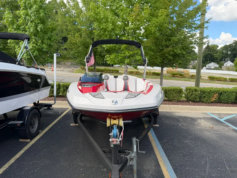 Slide: The Image of A 2017 Scarab 165 boat on a trailer, parked in a lot with trees in the background. - 3