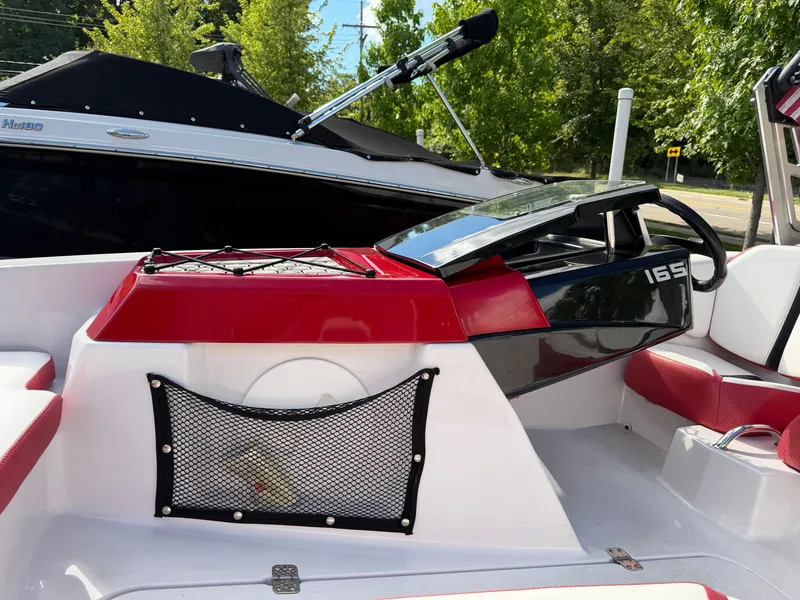 Slide: The Image of The image shows the cockpit of a 2017 Scarab 165 boat with red and white accents. - 17