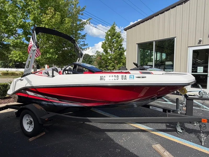 The Image of A red 2017 Scarab 165 boat on a trailer, parked in front of a building. - 0