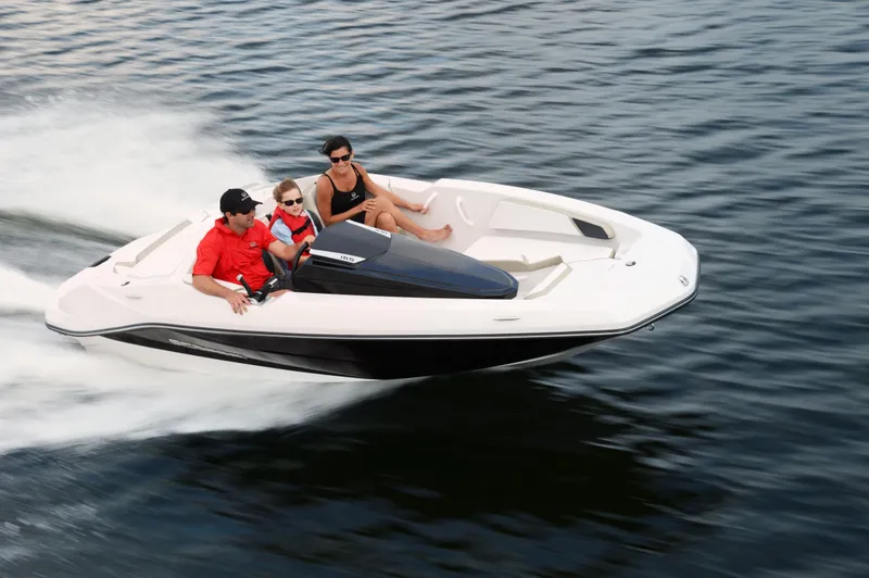 The Image of Three people ride in a white Scarab 165 motorboat speeding across the water. - 0