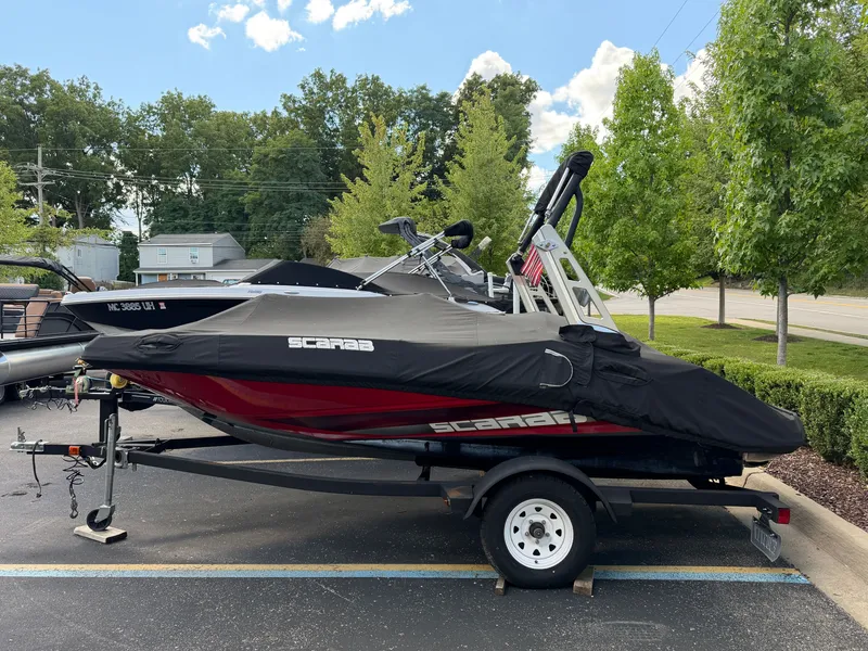 Slide: The Image of A 2017 Scarab 165 boat on a trailer, covered and parked in a lot. - 1