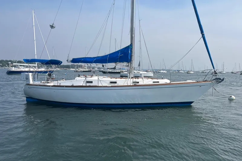 Slide: The Image of 1979 Tartan 37 sailboat with blue sail, anchored in a marina. - 1