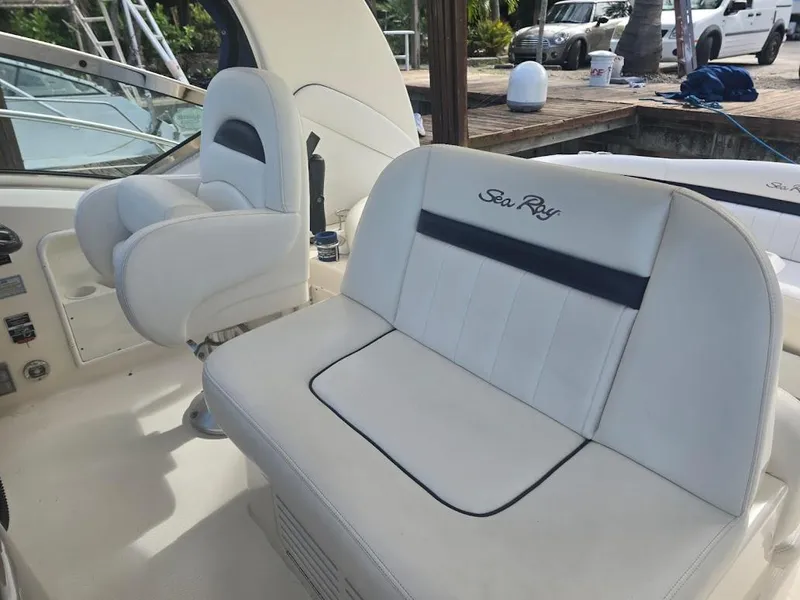 Slide: The Image of 2008 Sea Ray 40 Sundancer interior with white seating and helm, dockside view. - 9