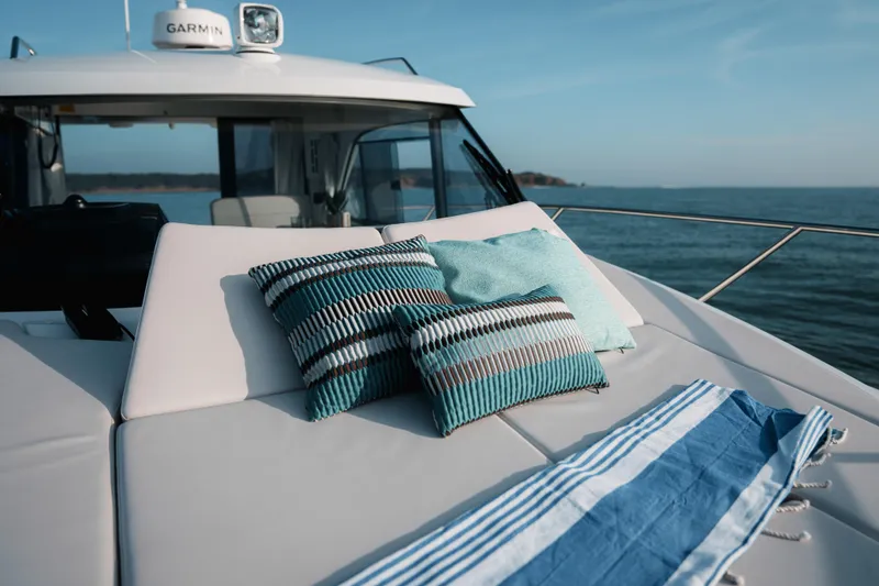 Slide: The Image of 2026 Beneteau Antares 9 V2 yacht with cushions and towel on deck, ocean view. - 16