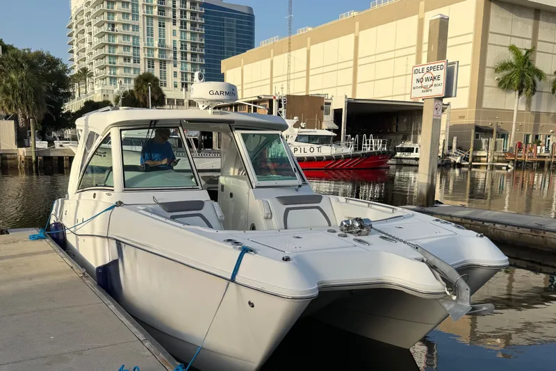 Slide: The Image of 2019 World Cat 320 DC boat docked in a marina, surrounded by urban buildings. - 2
