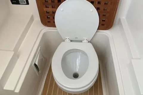 Slide: The Image of The toilet on a boat with wooden flooring and white walls. - 19
