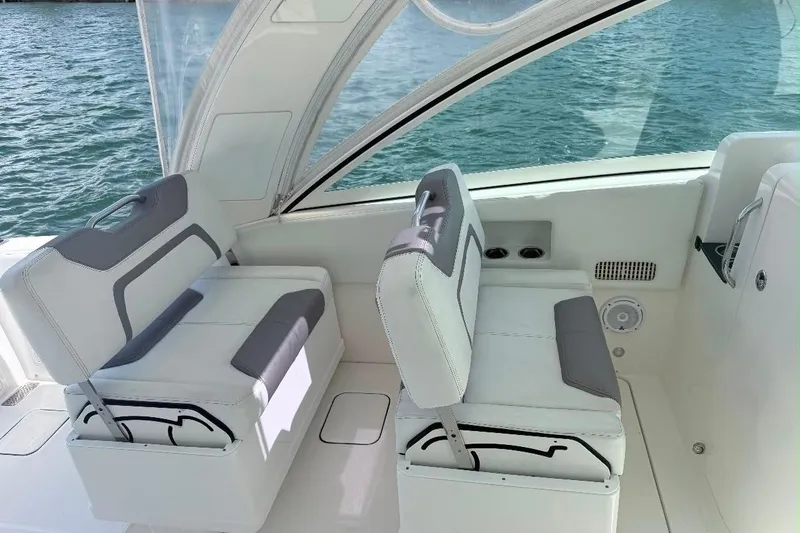 Slide: The Image of 2019 World Cat 320 DC boat interior with white and gray seating by the water. - 29