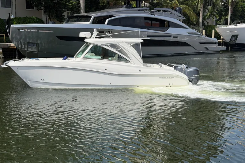 The Image of 2019 World Cat 320 DC boat cruising on a calm waterway, with luxury yachts in the background. - 0