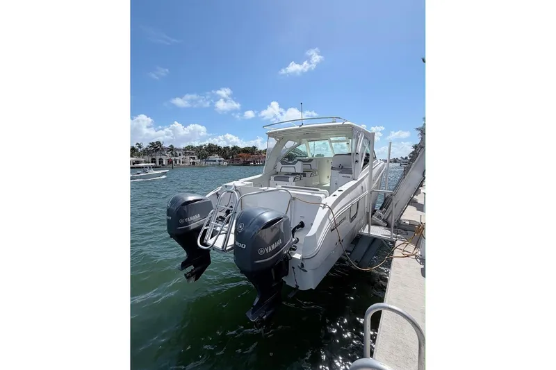 Slide: The Image of 2019 World Cat 320 DC boat docked with twin Yamaha engines, under a clear blue sky. - 13