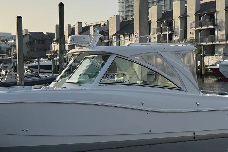 Slide: The Image of 2019 World Cat 320 DC boat docked in a marina, surrounded by buildings. - 1
