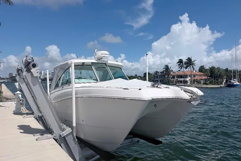 Slide: The Image of 2019 World Cat 320 DC boat docked by waterfront homes under a clear blue sky. - 9