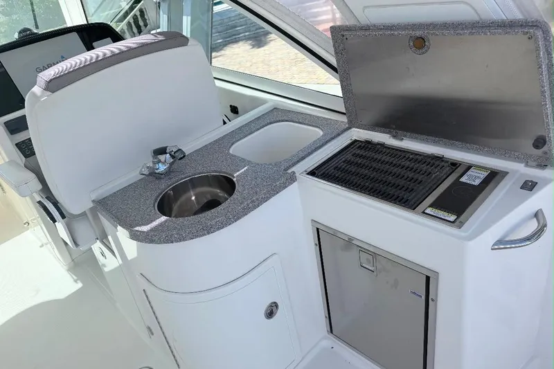 Slide: The Image of 2019 World Cat 320 DC boat interior with sink, grill, and storage. - 28