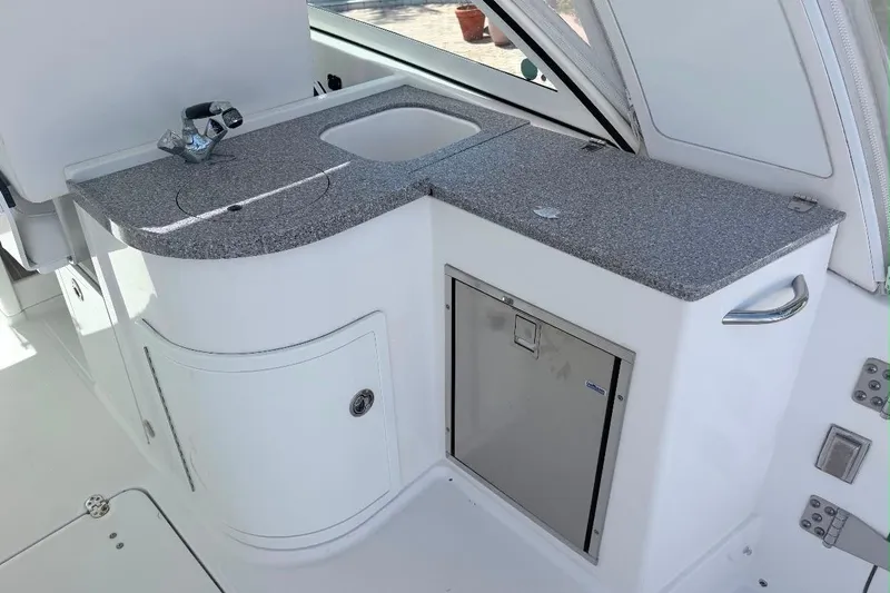 Slide: The Image of 2019 World Cat 320 DC boat kitchenette with sink, countertop, and storage. - 27