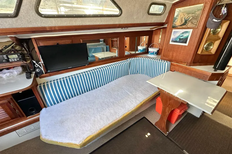 Slide: The Image of Interior of a 1976 Islander 36 sailboat with striped seating and a small table. - 14