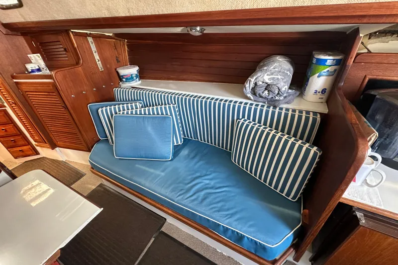Slide: The Image of Interior of a 1976 Islander 36 sailboat with blue striped cushions and wooden cabinetry. - 16