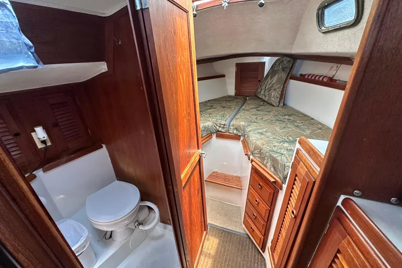 Slide: The Image of 1976 Islander 36 sailboat interior with wooden cabinetry, compact bathroom, and cozy sleeping area. - 17