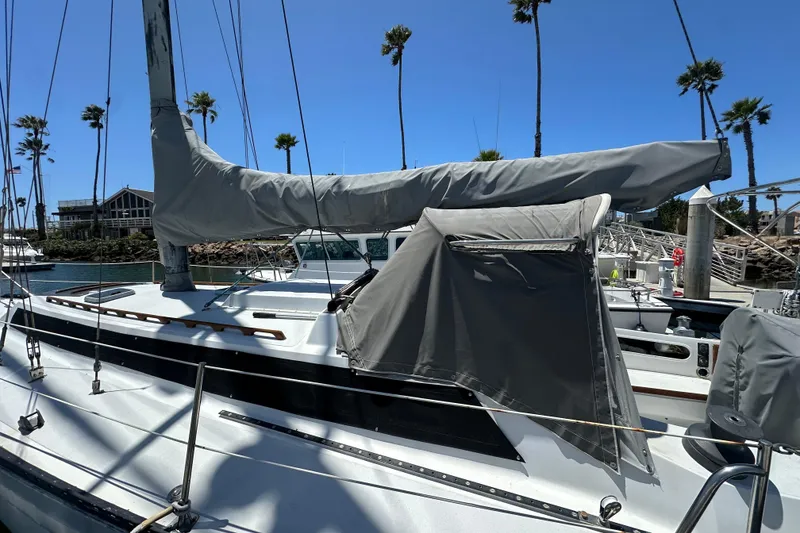 Slide: The Image of 1976 Islander 36 sailboat docked, covered sails, sunny marina, palm trees in background. - 22