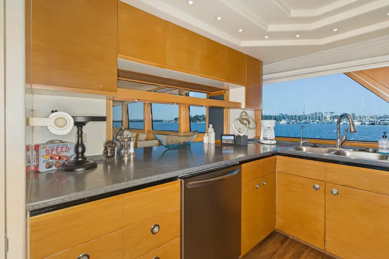 Slide: The Image of The kitchen of a 1990 Westport Crescent yacht with wooden cabinets and a view of the harbor. - 22