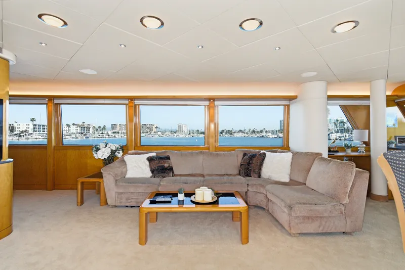 Slide: The Image of A luxurious salon with a large beige sofa and wooden table, overlooking the harbor. - 16