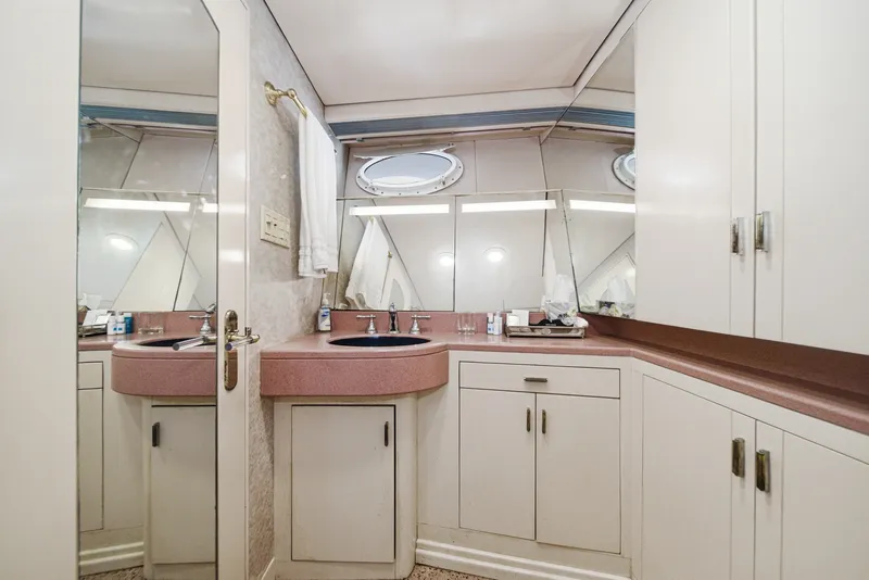 Slide: The Image of An elegant bathroom with a pink sink, white cabinets, and porthole windows on a yacht. - 49