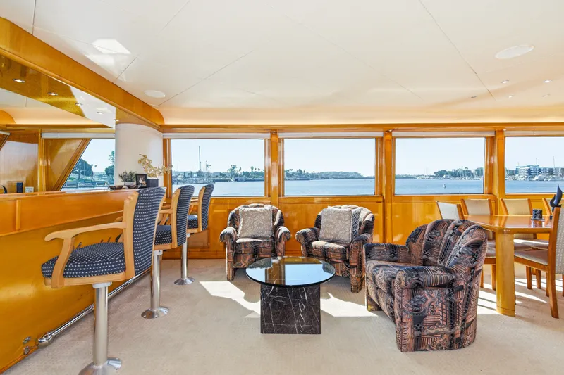 Slide: The Image of Luxurious salon with upholstered chairs, bar stools, and panoramic windows offering a view of the water. - 18