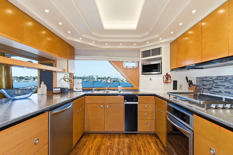 Slide: The Image of The yacht's kitchen features wooden cabinets, modern appliances, and a large window overlooking the harbor. - 20