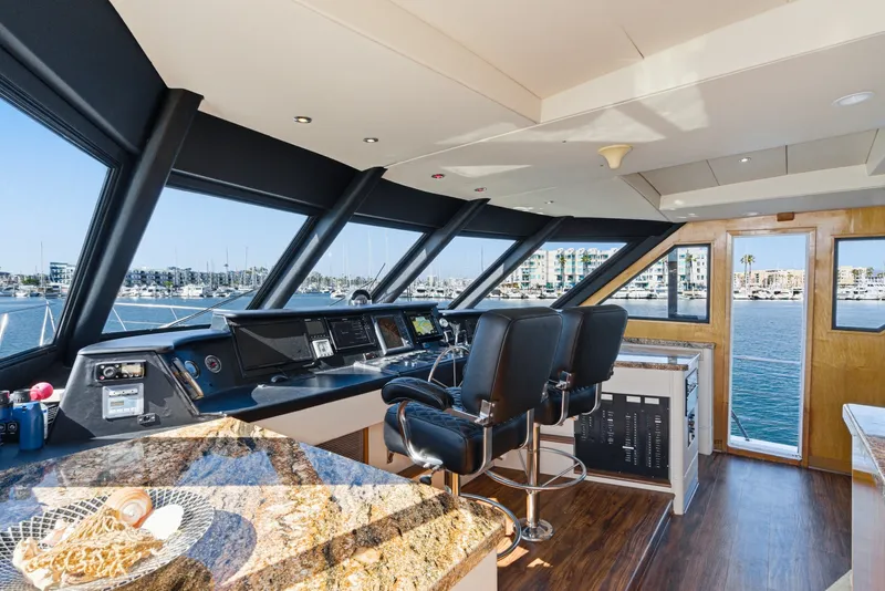 Slide: The Image of The helm of the 1990 Westport Crescent features luxurious seating and modern navigation equipment overlooking the marina. - 37