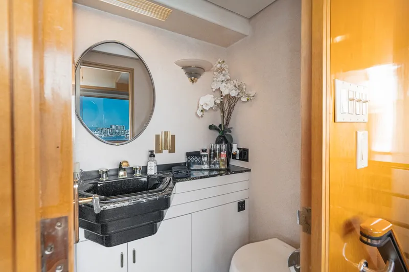 Slide: The Image of An elegant yacht bathroom with a round mirror, black sink, and orchids. - 24