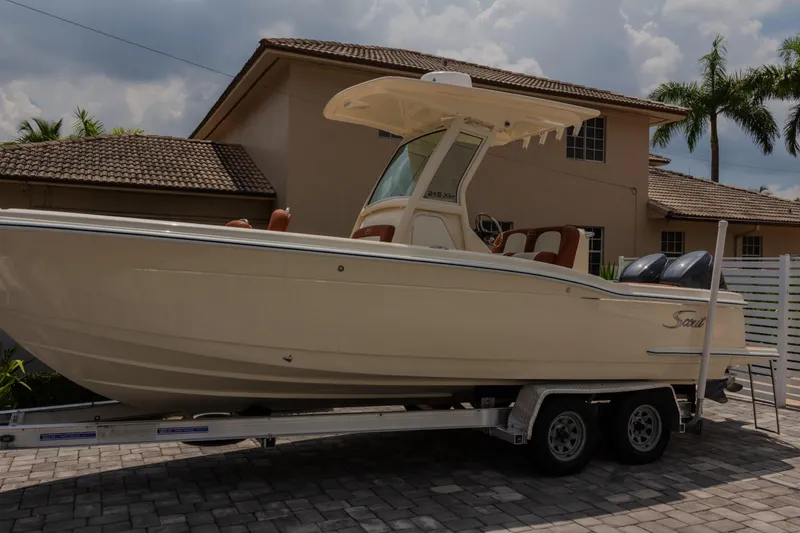 The Image of 2014 Scout 245 XSF boat on trailer, parked in front of a house. - 0