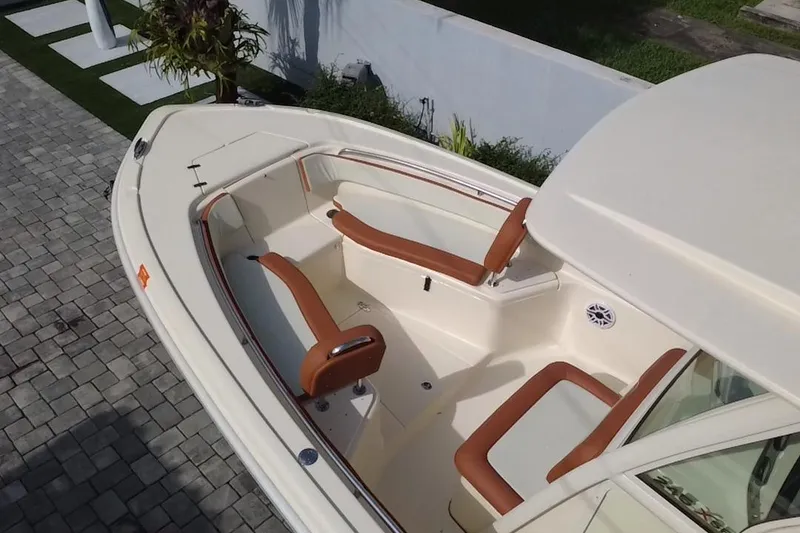 Slide: The Image of 2014 Scout 245 XSF boat with tan seating, docked on a stone-paved area. - 14